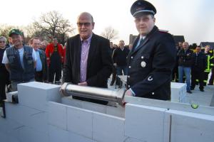 Bürgermeister Manfred Cordes und Ortsbrandmeister Matthias Meyer legten eine Zeitkapsel in die Wand.